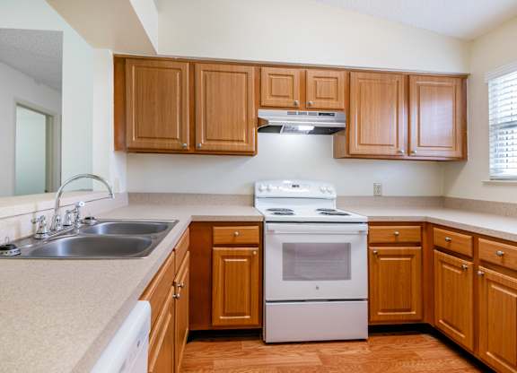 A kitchen with wooden cabinets and a white stove top oven Fishermans Landing Apartments in Ormond Beach, FL