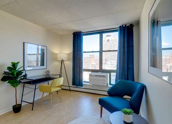 Home office with a blue chair and a desk and a window at Ninth Square Apartments. at Ninth Square Apartments, New Haven