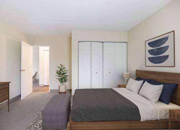 A bedroom with a bed and a dresser and a closet at North Stoughton Village Apartments in Stoughton, MA