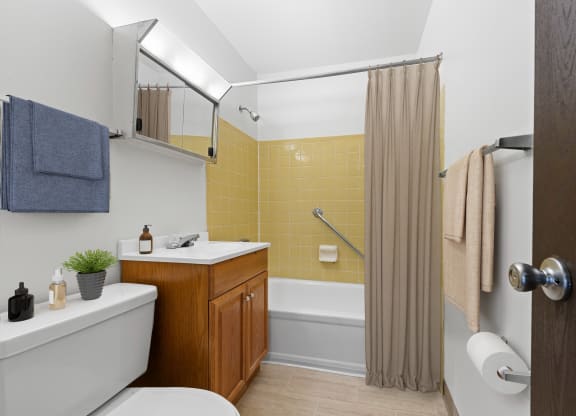 a bathroom with a white toilet next to a bathtub with a shower curtain at Huntingdon Village Apartments, Hunker