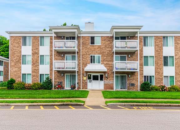 an apartment building with a sidewalk and grassat North Stoughton Village, Stoughton, Massachusetts