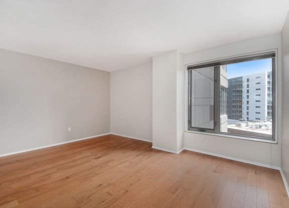 an empty living room with wood floors and a large window