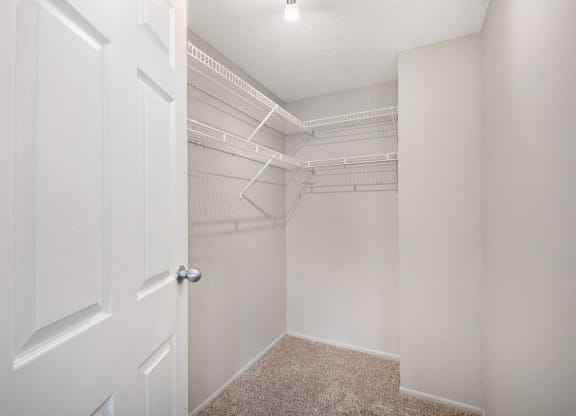 an empty closet with white walls and a white door