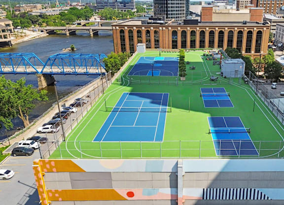 A tennis court is located on a rooftop with a river and buildings in the background.