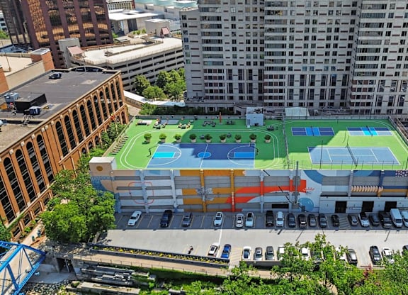 A large building with a green, blue and orange tennis court on the roof.