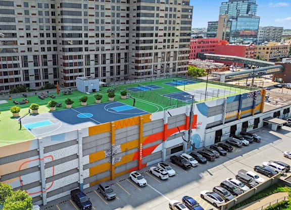 A tennis court is located on the roof of a parking garage.