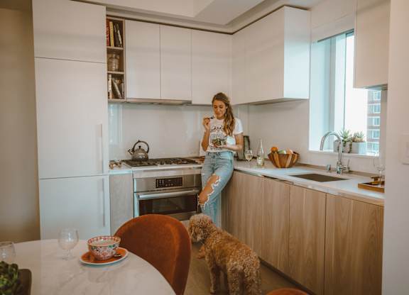 A woman is standing in a kitchen with a dog.