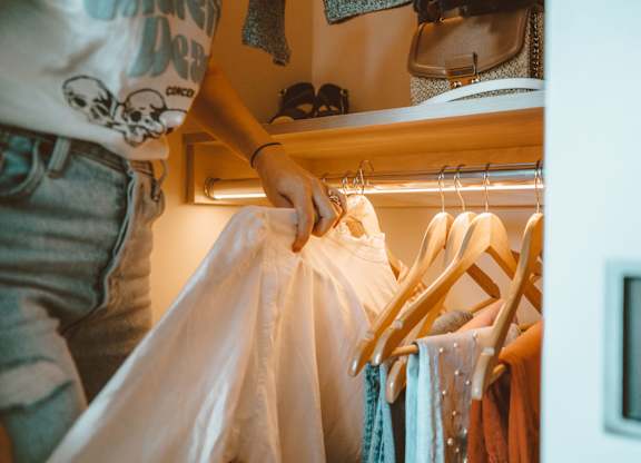 A person is hanging a white shirt on a wooden hanger.