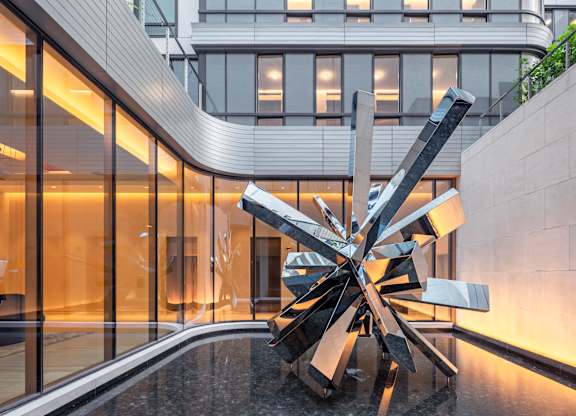 A large, modern sculpture sits in the middle of a reflective pool.