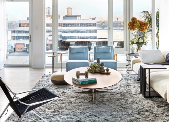 a living room with blue chairs and a rug and a large window