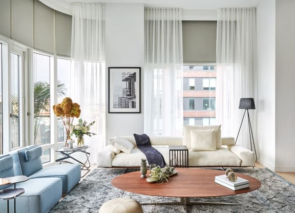 a living room with white curtains and a couch and a table