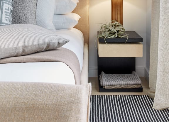 a bedroom with a bed with white pillows and a nightstand with a lamp