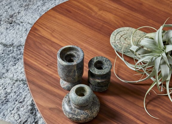 a wooden table with three vases and a plant on it
