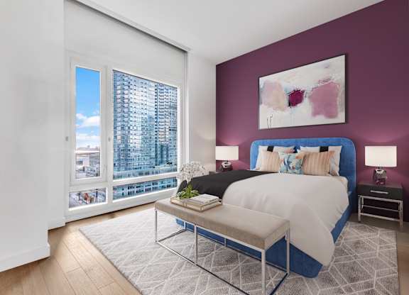 A bedroom with a large bed and a view of a city skyline.