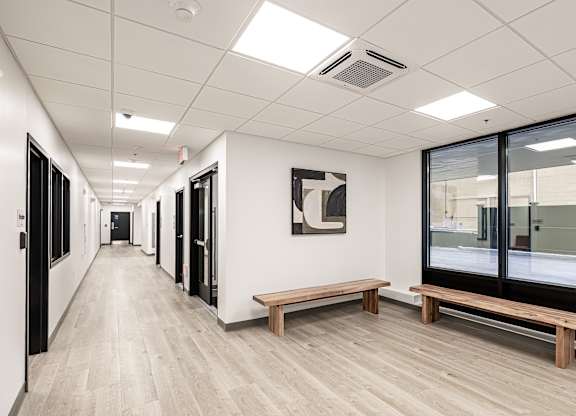 A long hallway with a bench and a painting on the wall.