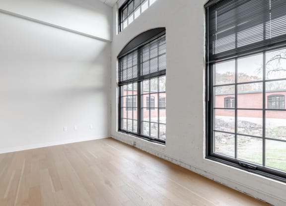 an empty living room with large windows and wood floors