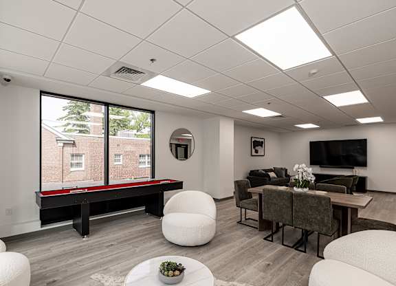 A living room with a white couch, a black table, and a window with a view of a building.