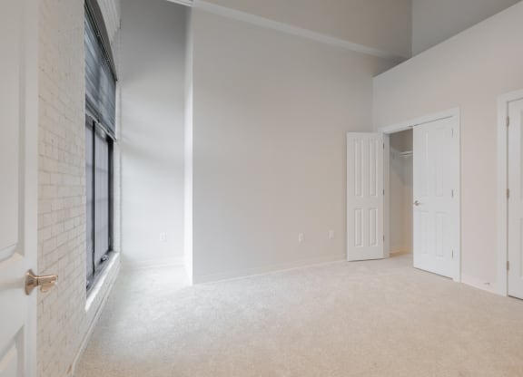 an empty living room with white carpet and white doors and a window