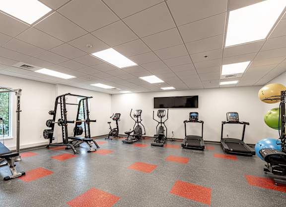 A gym with a variety of equipment including treadmills, weights, and exercise machines.