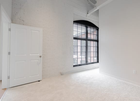 an empty room with a window and a white door