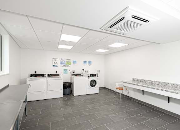 A laundry room with washers and dryers and a bench.