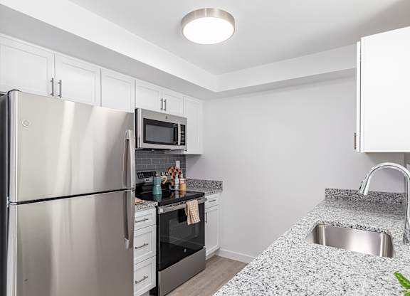 A kitchen with a stainless steel refrigerator, microwave, oven, and sink.