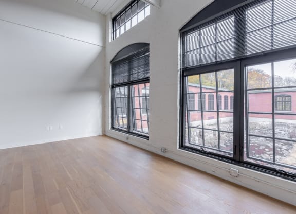 an empty living room with large windows and wood floors