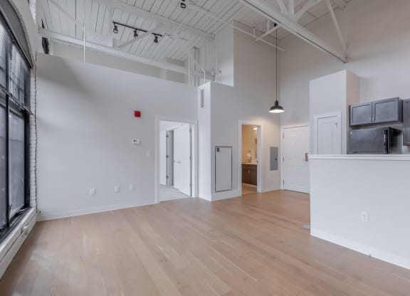 a living room and kitchen with white walls and wood floors