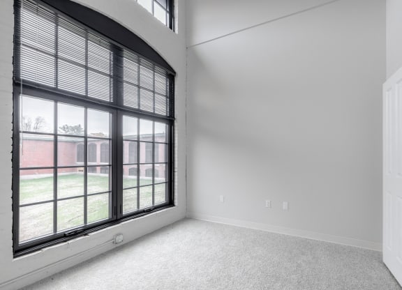 an empty living room with large windows and white walls