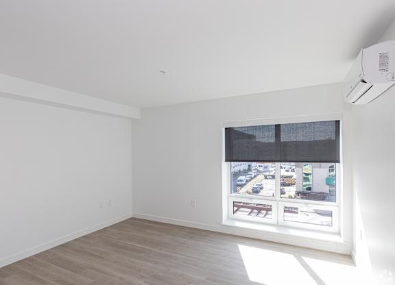 A room with a window showing a view of a street with cars and buildings.