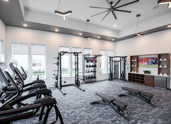 A gym with treadmills, weights, and exercise benches at 55 Fifty at Northwest Crossing, Houston, TX 77092