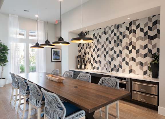 A modern dining room with a long wooden table and grey chairs at 55 Fifty at Northwest Crossing, Houston, TX 77092