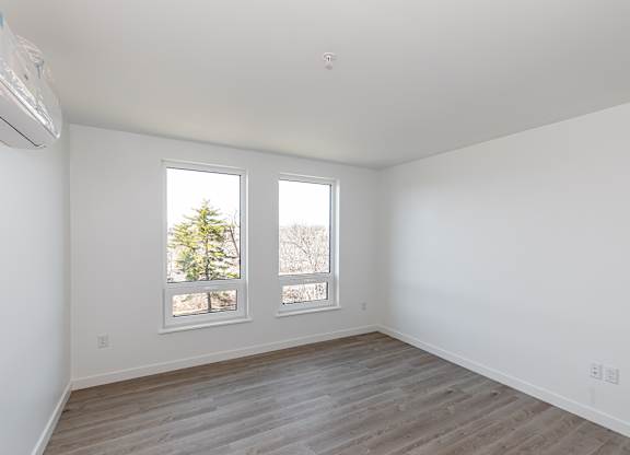 A room with a window and a wooden floor.