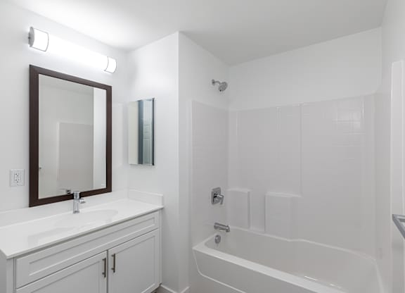 A white bathroom with a white tub and a white sink.