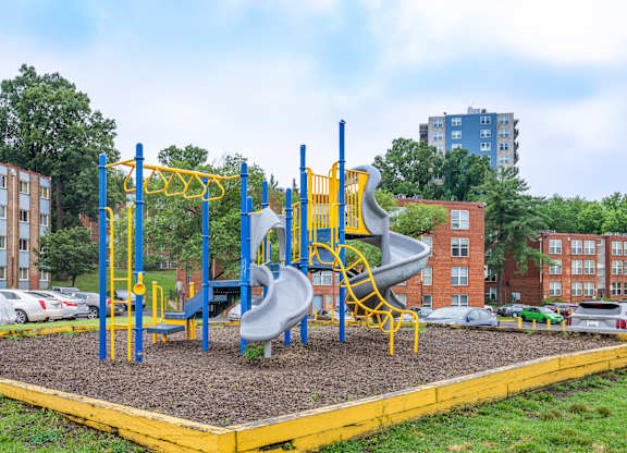 A playground with a yellow and blue slide and a yellow and blue climbing frame.
