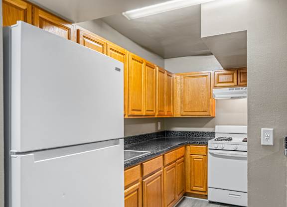 A kitchen with a white refrigerator and wooden cabinets.