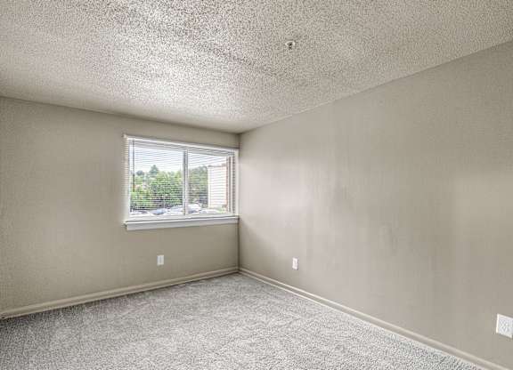 A room with a window and carpeted floor.