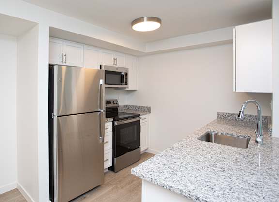 A kitchen with a stainless steel refrigerator, microwave, oven, and sink.at The Camelot, West Hartford, CT 06119  