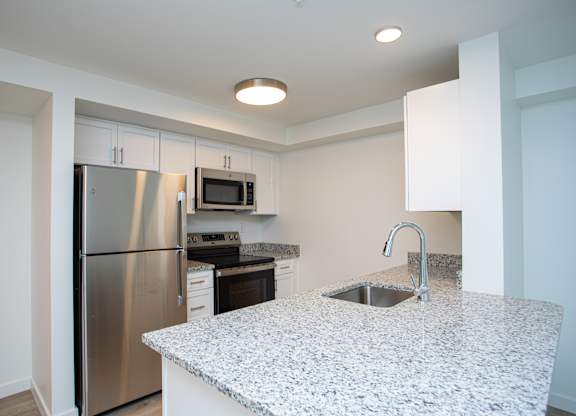 A kitchen with a granite countertop and stainless steel appliances.at The Camelot, West Hartford  
