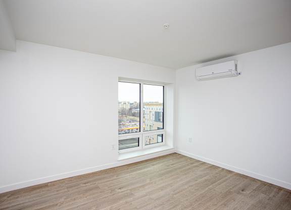 Empty room with a window and a wall-mounted air conditioner.at The Camelot, West Hartford, CT  