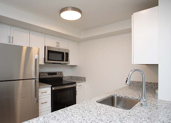 A kitchen with a stainless steel refrigerator, microwave, oven, and sink.at The Camelot, West Hartford Connecticut  