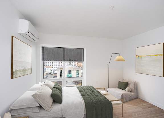A bedroom with a bed, a couch, and a window with a view of the city.