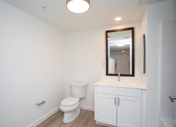 A white bathroom with a toilet, sink and mirror.at The Camelot, West Hartford, CT 06119  