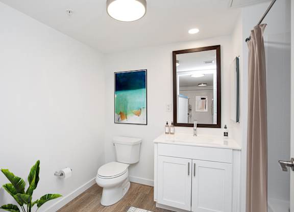 A white bathroom with a toilet, sink, and a mirror.