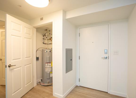 A white door is open to a hallway with a water heater in the corner.at The Camelot, Connecticut, 06119
