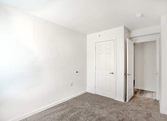 A white door is in a room with a carpet.