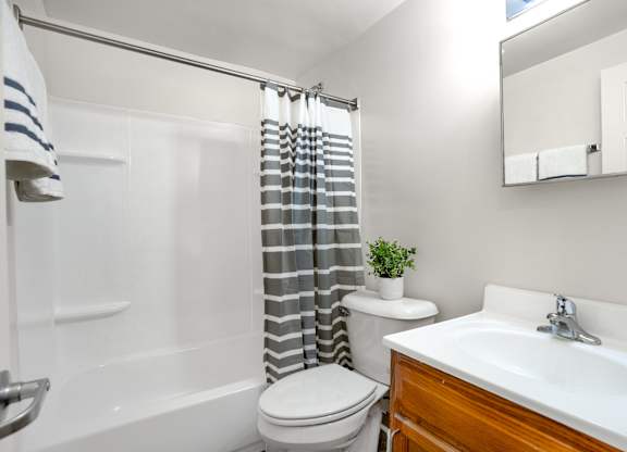 A bathroom with a white toilet, a white sink, and a striped shower curtain.