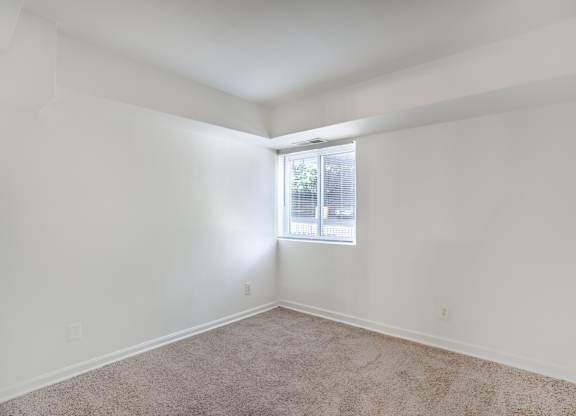 A room with a window and carpeted floor.