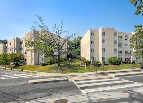 A street view of a residential area with buildings, trees, and a crosswalk.