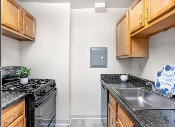 A kitchen with a stove, sink and cabinets.
